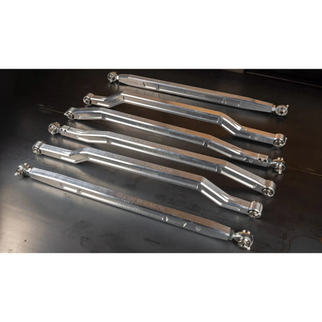 Set of metal control arms on a dark surface